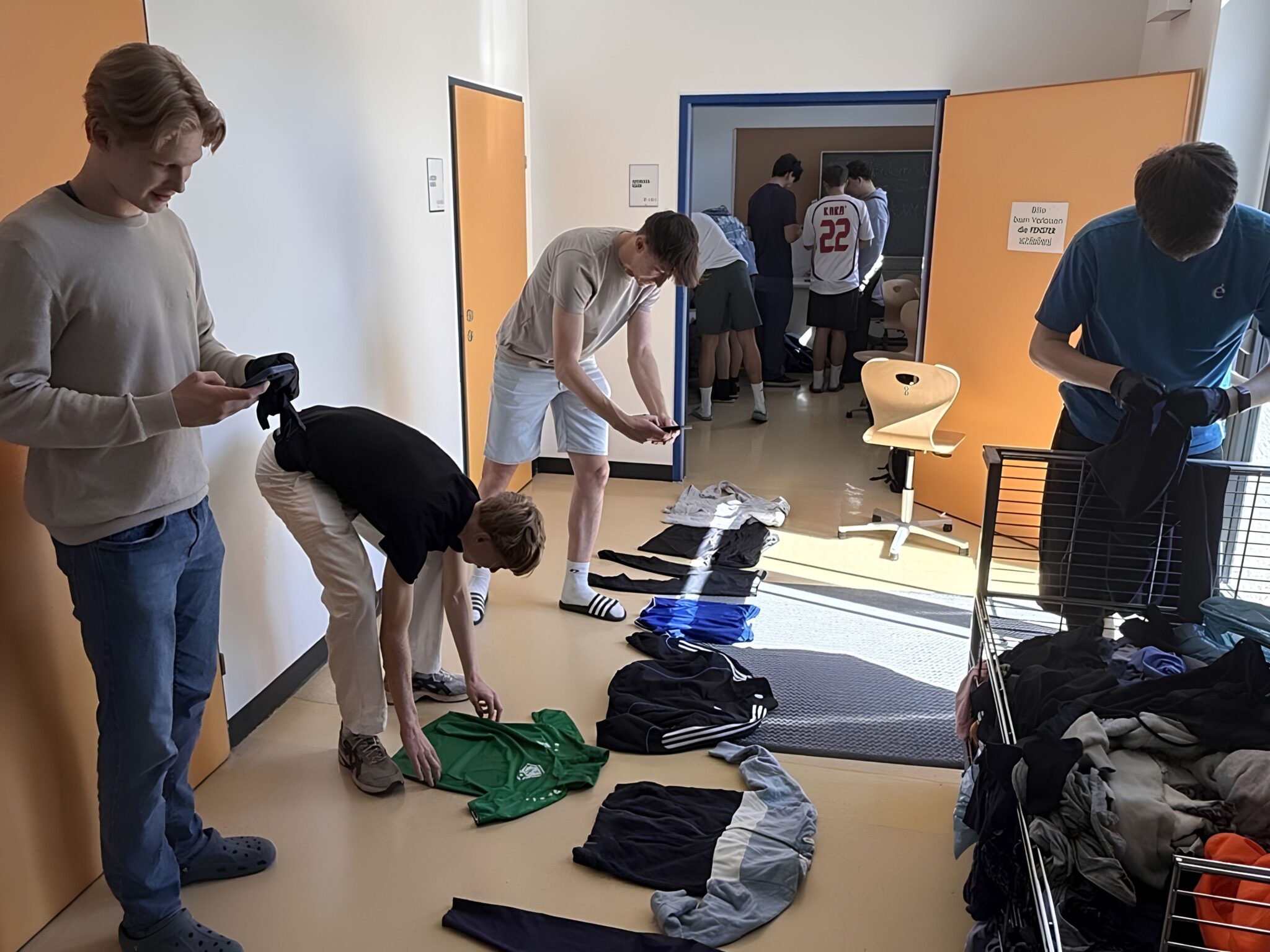 Jugendliche sortieren Sportkleidung in einem Schulgebäude in Österreich