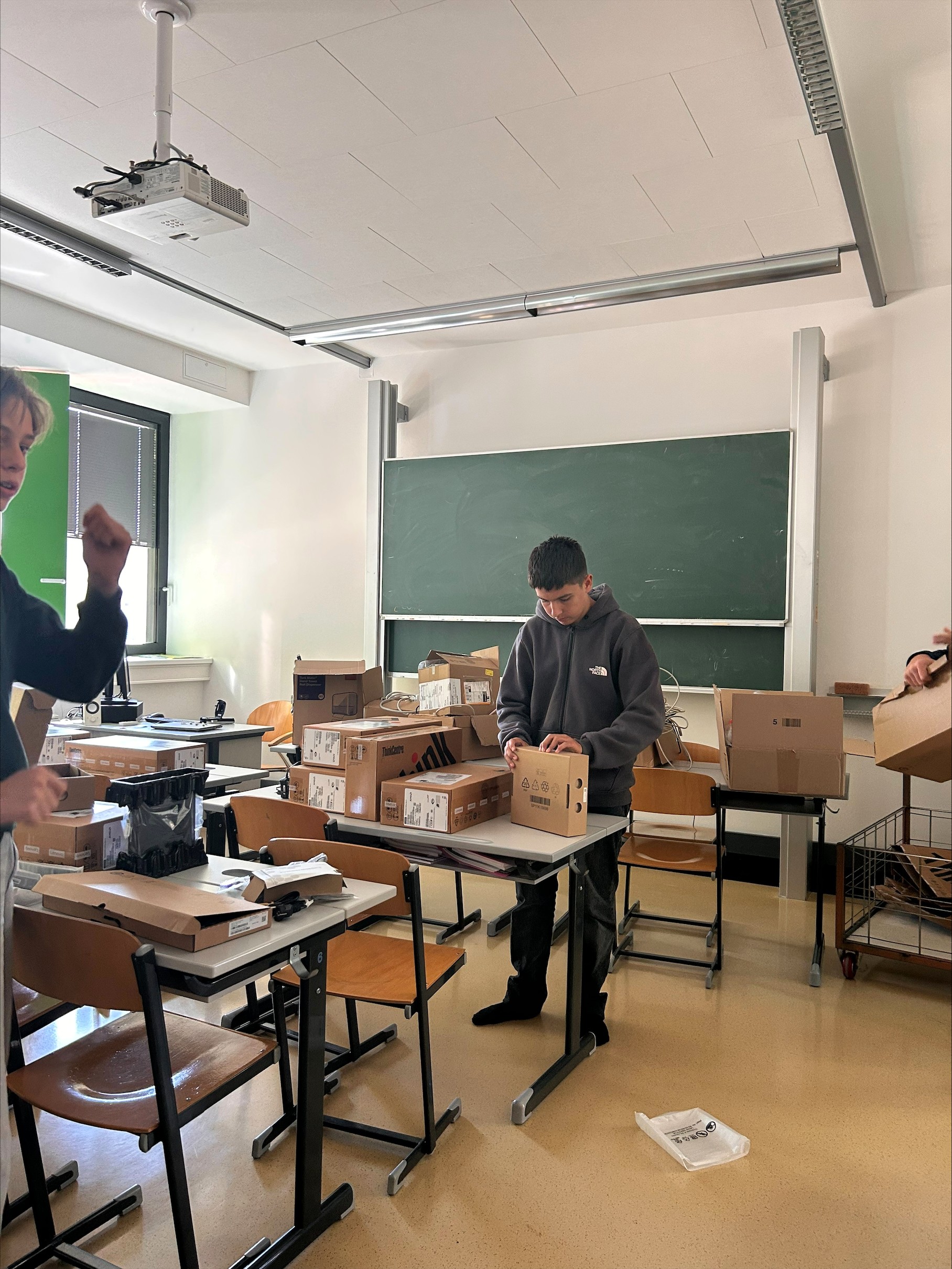Schüler packen Laptops in Kartons in einem Klassenzimmer in Österreich