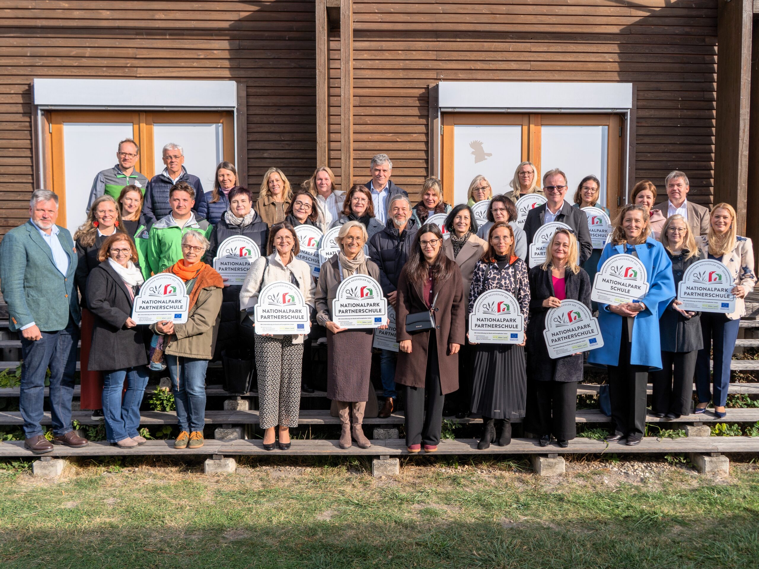 Nationalpark Neusiedler See: Partnerschulen-Delegation posiert vor Holzhaus